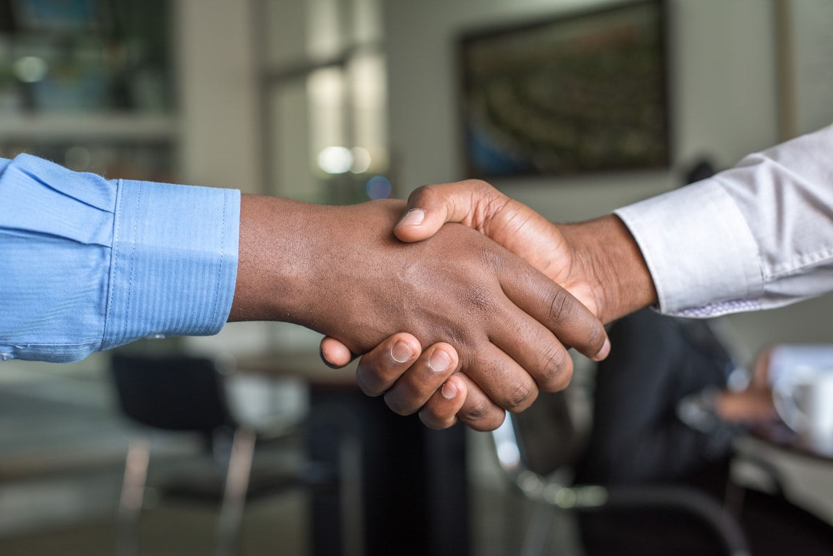Two people shaking hands across a conference table