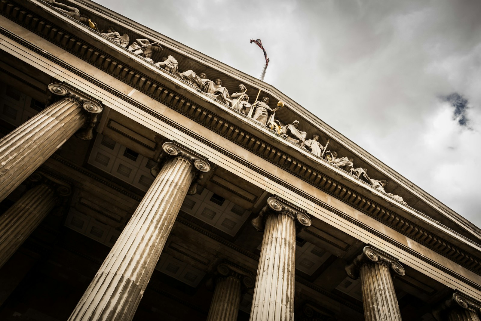 Stone pediment and ionic columns of a classical courthouse against a stormy sky